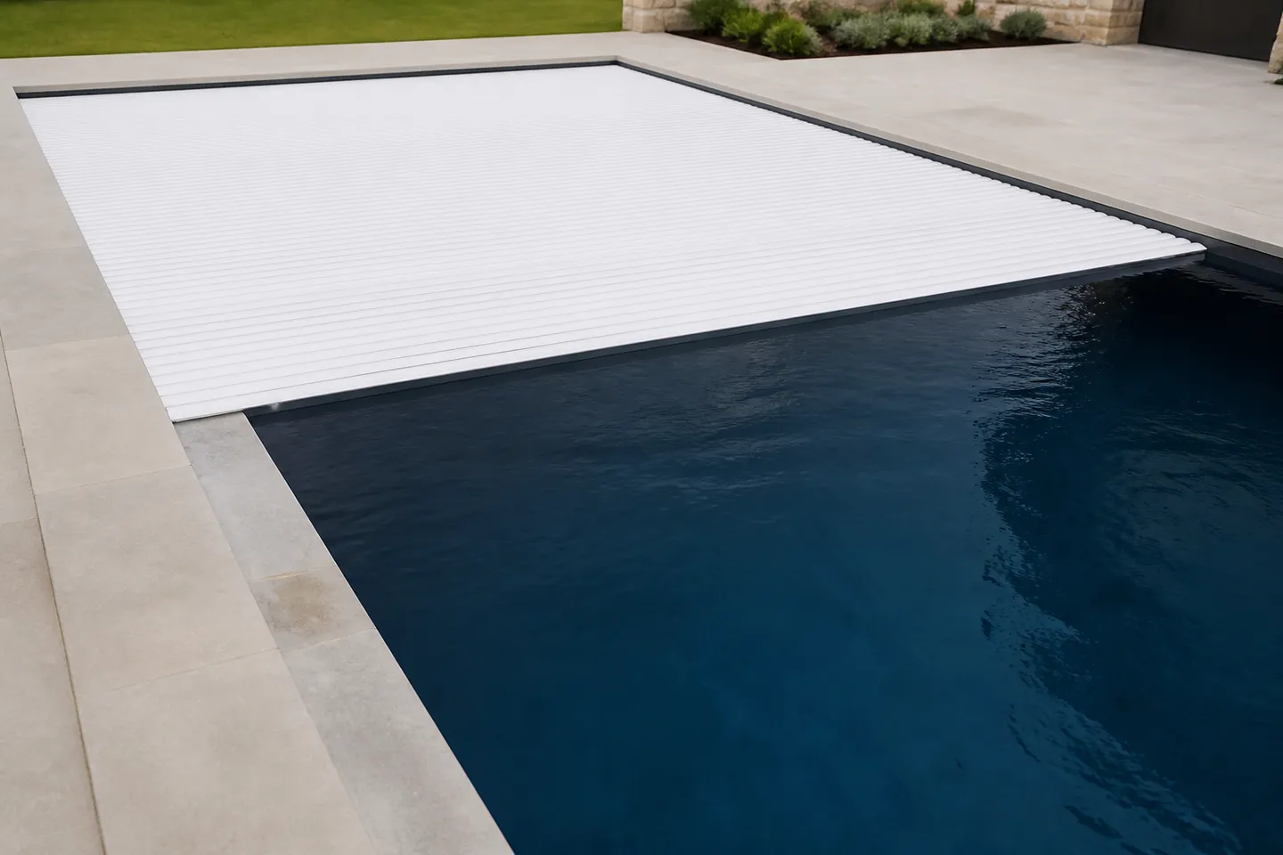 Rectangular swimming pool with a closed automatic cover on a concrete deck