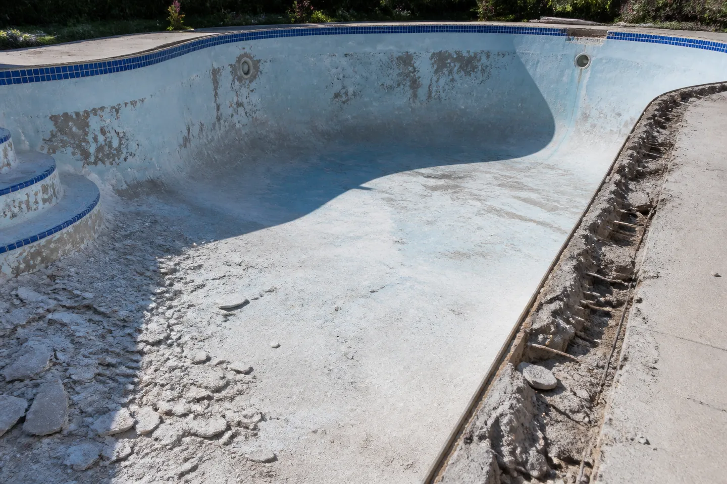 Drained swimming pool during a renovation with coping removed
